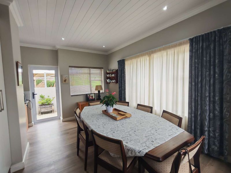 A bright dining room featuring wood-look flooring, a tongue-and-groove ceiling, and direct access to an outdoor patio area through a glass-paneled door.