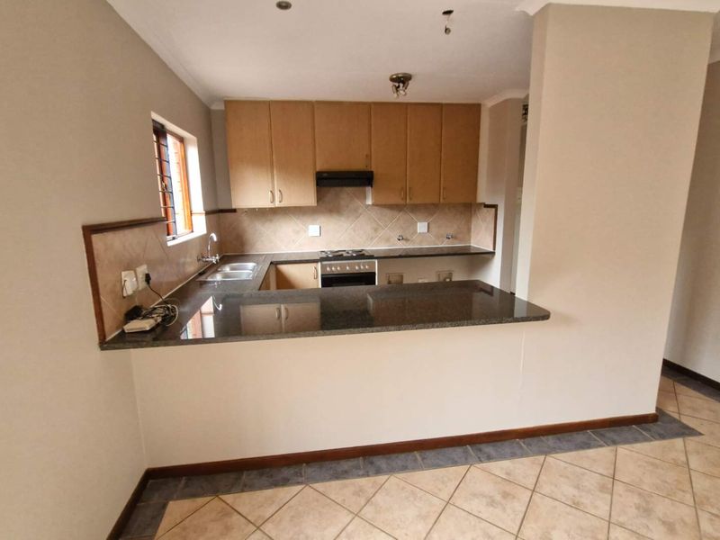 A functional kitchen featuring granite countertops, built-in cabinetry, a breakfast bar, and integrated appliances, offering a clean and practical layout.