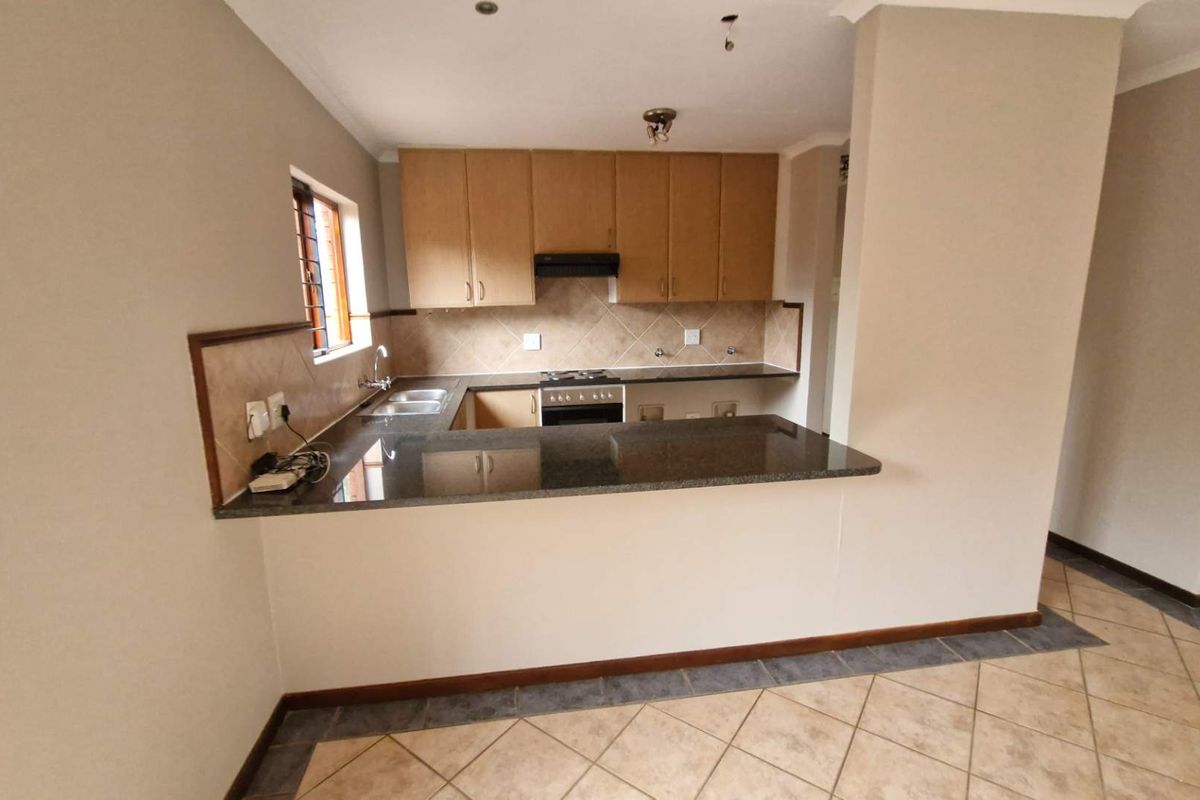 A functional kitchen featuring granite countertops, built-in cabinetry, a breakfast bar, and integrated appliances, offering a clean and practical layout.