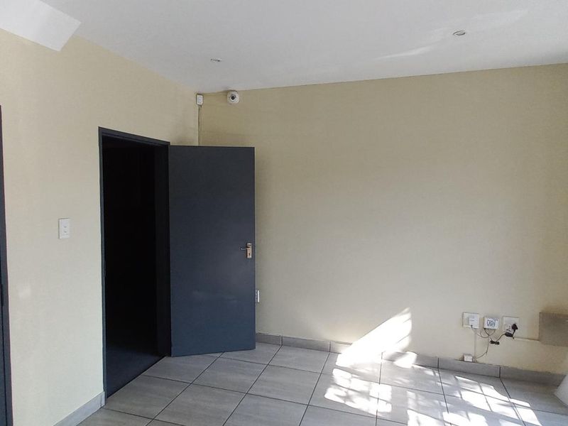 A functional office space featuring tiled flooring, recessed ceiling lighting, security camera, and integrated alarm system keypad.