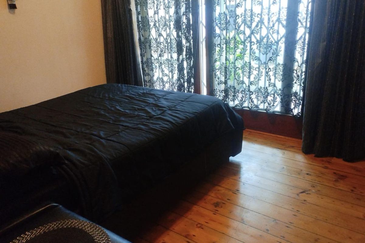 A bedroom featuring natural hardwood flooring and a large sliding glass door providing access to the exterior.