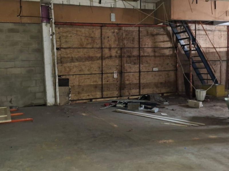 An industrial utility space featuring exposed concrete block walls, a metal staircase, and an open-plan layout suitable for renovation or storage.