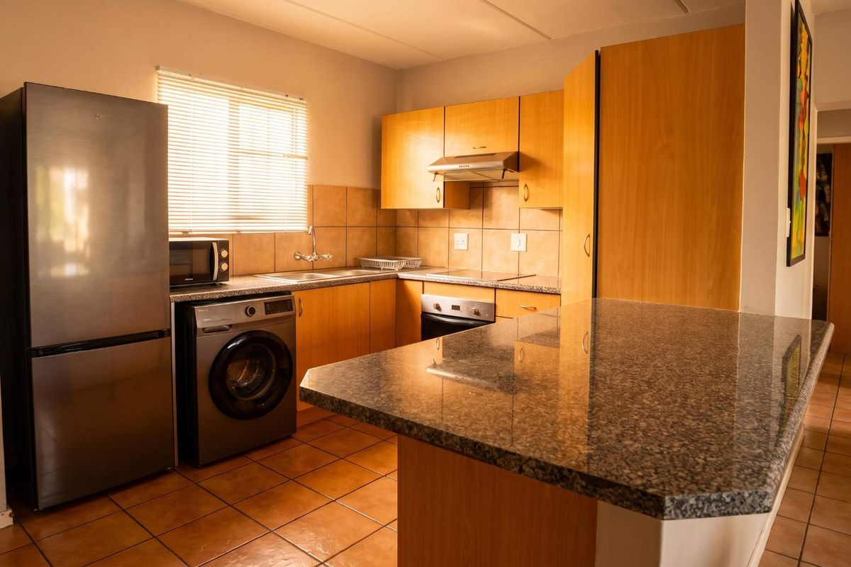 Functional kitchen featuring laminate cabinetry, granite countertops, a breakfast bar, and tiled flooring, offering a practical layout for daily meal preparation.