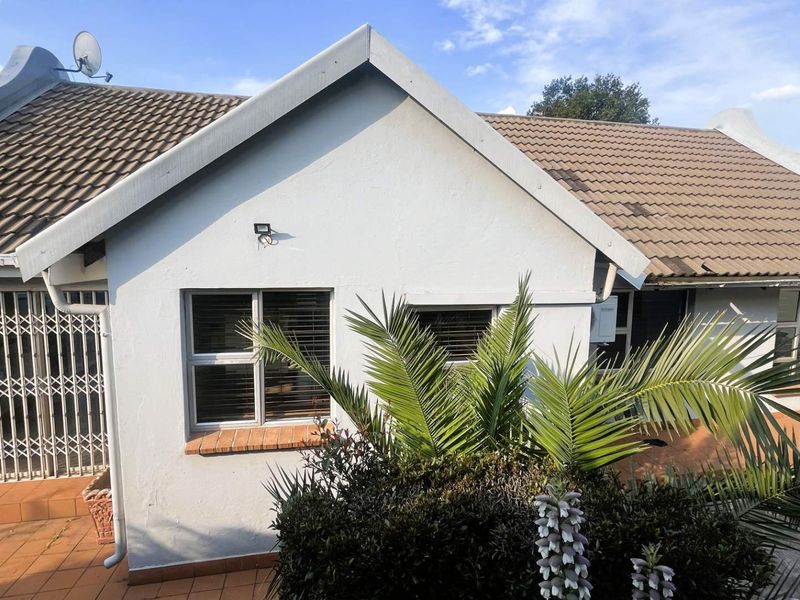 Rear exterior view of the house featuring a tiled roof, brick patio area, and security gates on the windows.