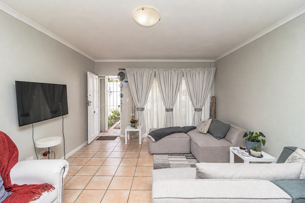 A bright living room featuring tiled flooring, a ceiling light fixture, and direct access to an outdoor area through a sliding glass door.
