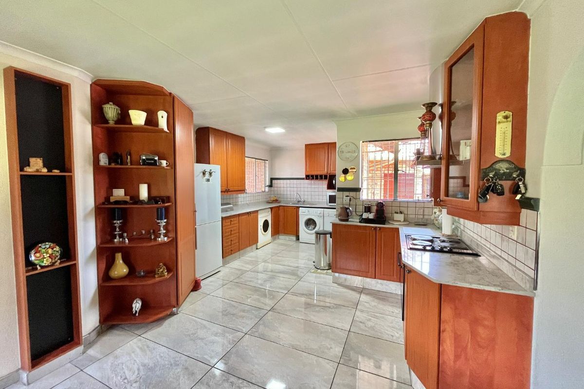 Spacious kitchen featuring wood-finish cabinetry, tiled flooring, integrated gas hob, and dedicated laundry appliance connections.