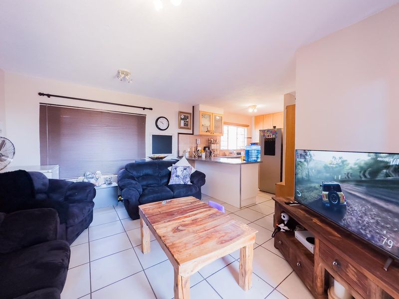 Open plan living area featuring tiled flooring and a functional kitchen with breakfast bar, creating a combined space for dining and relaxation.
