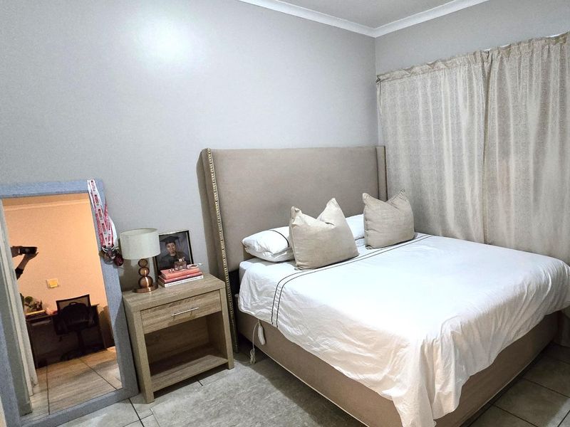 A functional bedroom featuring tiled flooring and neutral wall finishes, providing a comfortable and well-maintained living space.