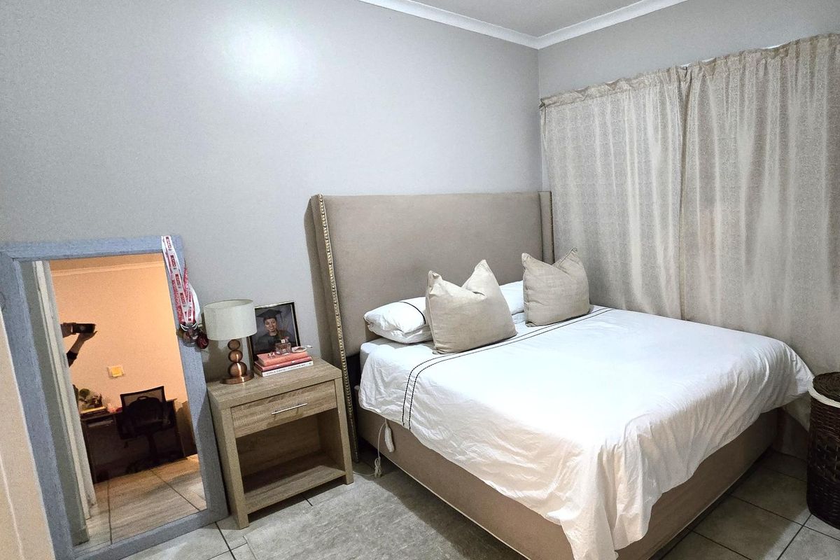 A functional bedroom featuring tiled flooring and neutral wall finishes, providing a comfortable and well-maintained living space.