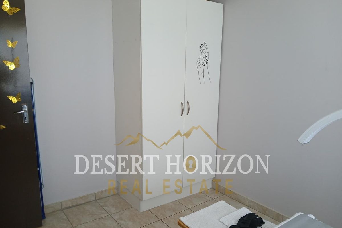 A bedroom featuring tiled flooring and a built-in white wardrobe.