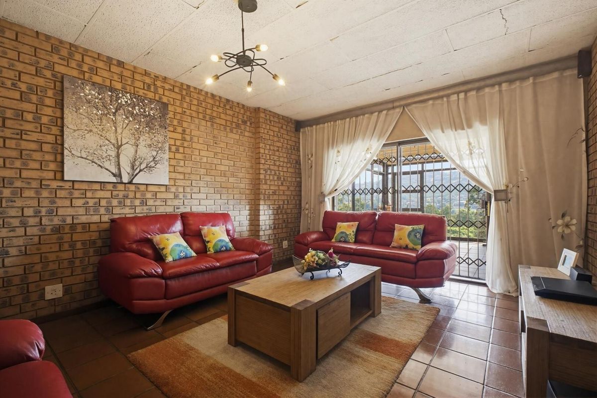 A living room featuring exposed brick walls, tiled flooring, and a sliding door with security gate leading to an outdoor area.