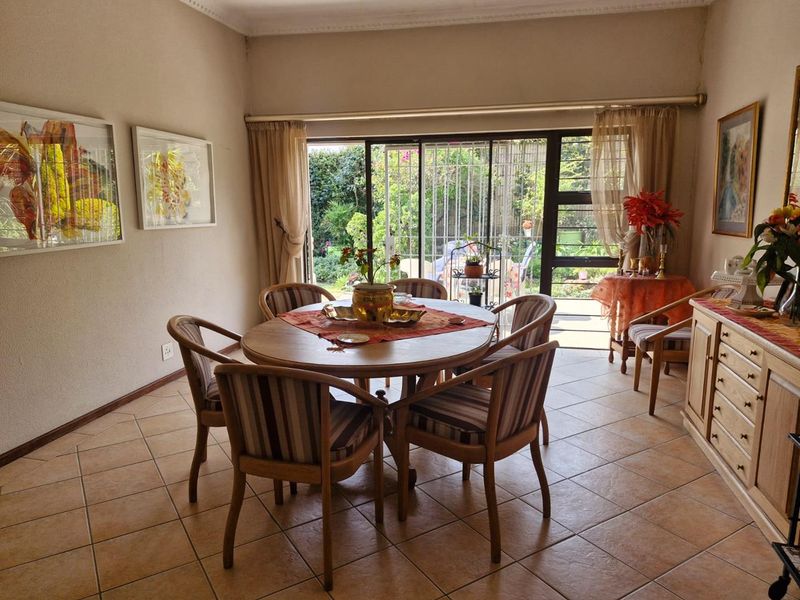 A dining room featuring tiled flooring and a large sliding glass door providing direct access to the garden.