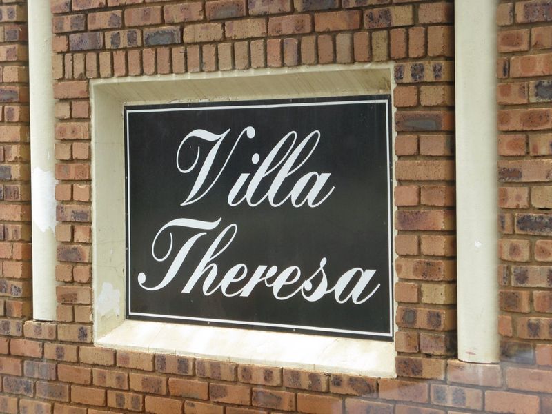 A close-up view of the Villa Theresa complex signage mounted on a face brick exterior wall.