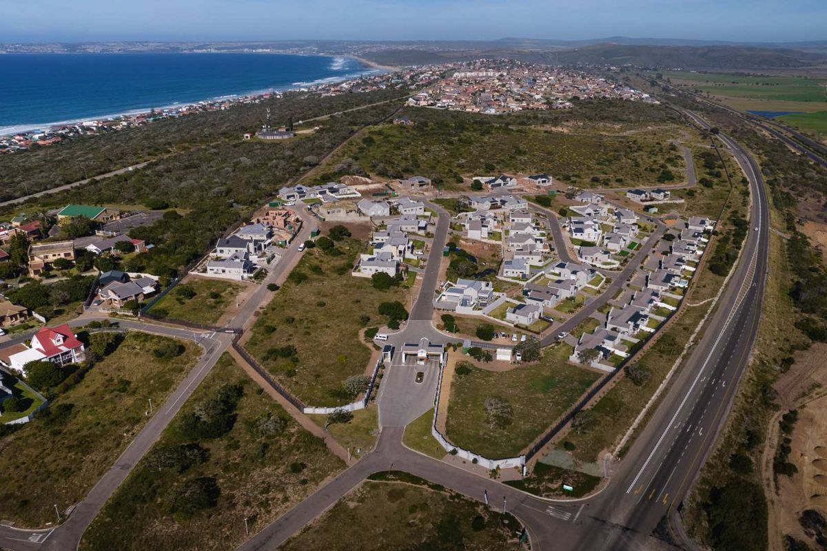 Aerial view of a residential estate development featuring a gated entrance, internal road network, and proximity to the coastline.