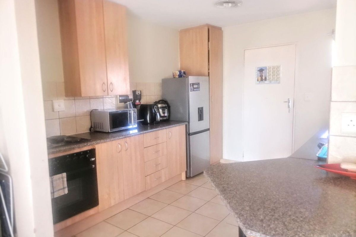 A functional kitchen featuring light wood cabinetry, granite-look countertops, tiled flooring, and a built-in oven with a breakfast nook extension.