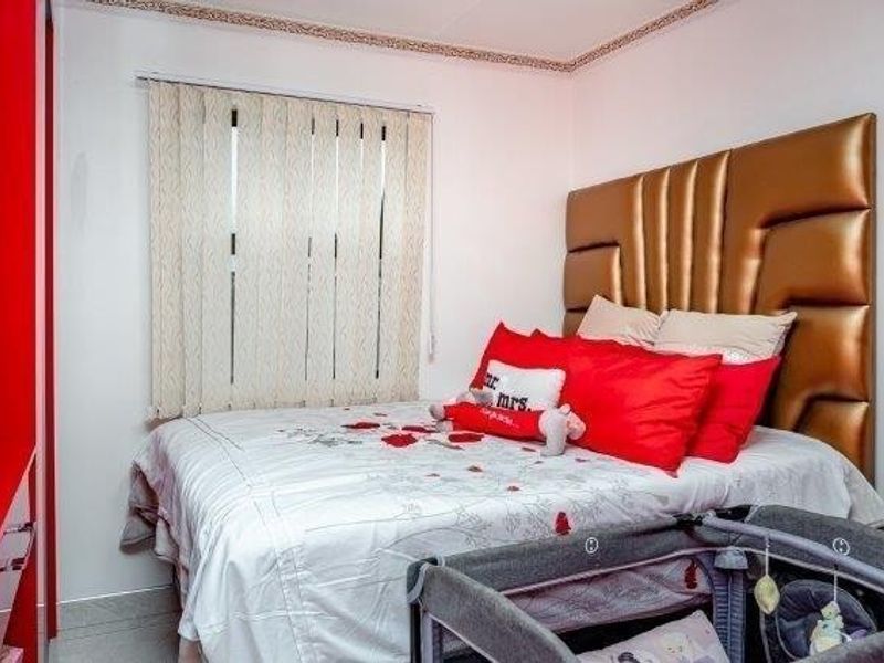 A bedroom featuring a built-in wardrobe, vertical window blinds, and decorative ceiling coving.