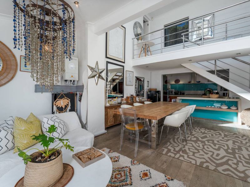 Open-plan living and dining area featuring a mezzanine level with stainless steel balustrades, hardwood flooring, and an integrated kitchen space.