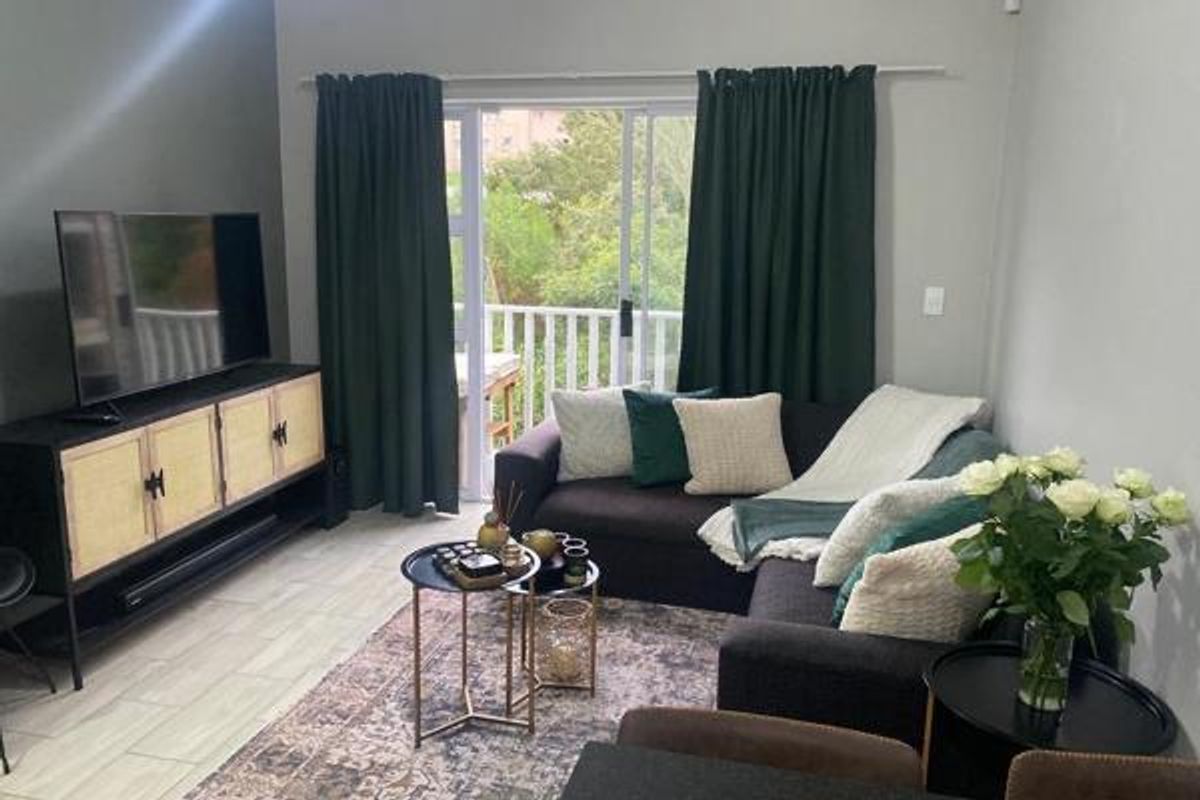 A comfortable living room featuring tiled flooring and a large sliding glass door that provides access to an outdoor balcony area.