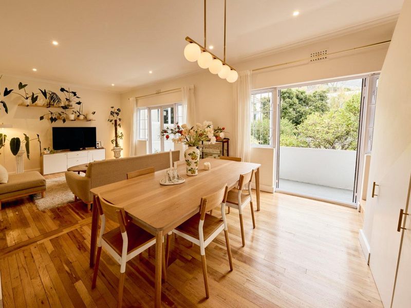 Bright open-plan living and dining area featuring polished hardwood floors, recessed lighting, and large sliding doors leading to a private balcony.