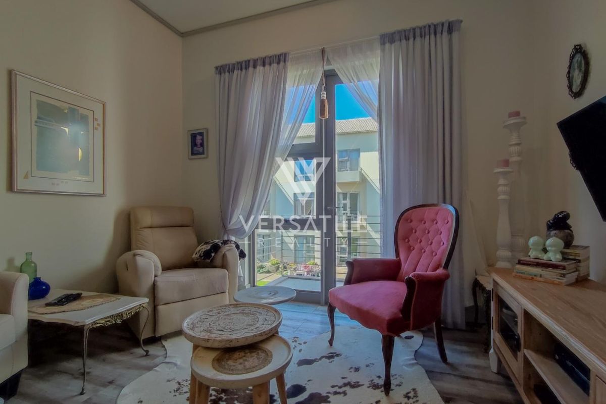 A cozy living room featuring laminate flooring and a glass sliding door providing access to an outdoor balcony area.