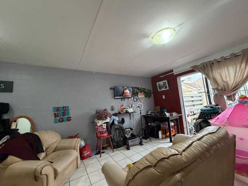 A living room area featuring tiled flooring and a sliding glass door providing access to the exterior.