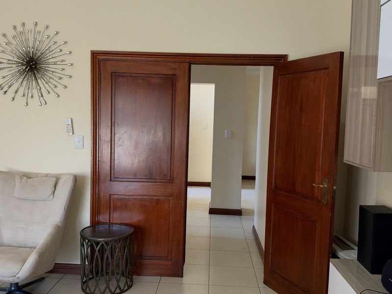 A view through a set of double wooden doors leading into a tiled hallway area.