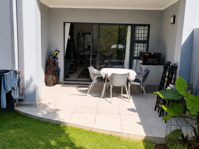 A covered patio area with tiled flooring, providing seamless indoor-outdoor flow through large sliding glass doors to the garden.