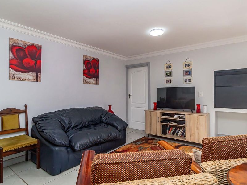 A comfortable living room featuring tiled flooring, crown molding, and a built-in wall niche, providing a functional and well-maintained space.
