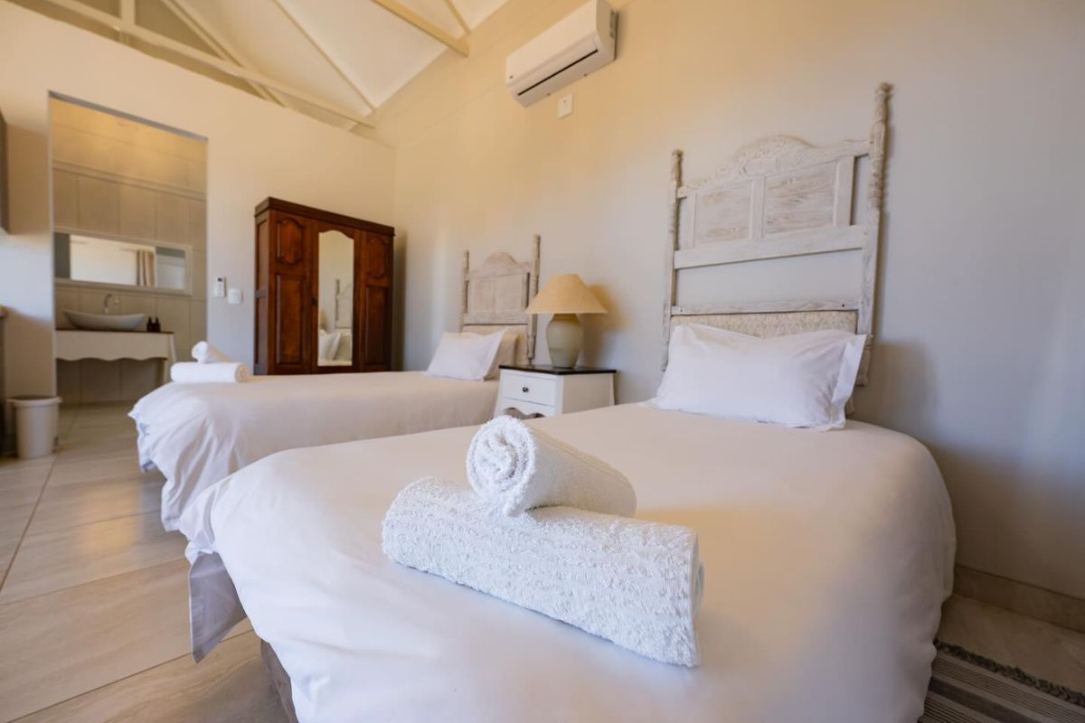 Spacious bedroom featuring high vaulted ceilings, tiled flooring, and an en-suite bathroom area, equipped with a wall-mounted air conditioning unit.