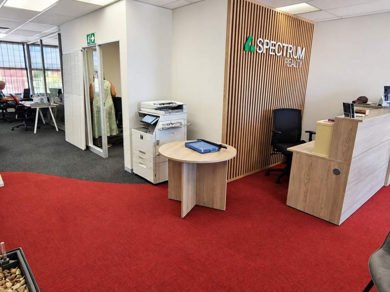 Professional office reception area featuring a modern slatted wood accent wall, reception desk, and large windows providing ample natural light.