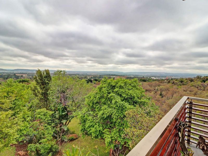 Elevated view overlooking a lush, wooded landscape and distant horizon from a balcony with a timber and metal railing.