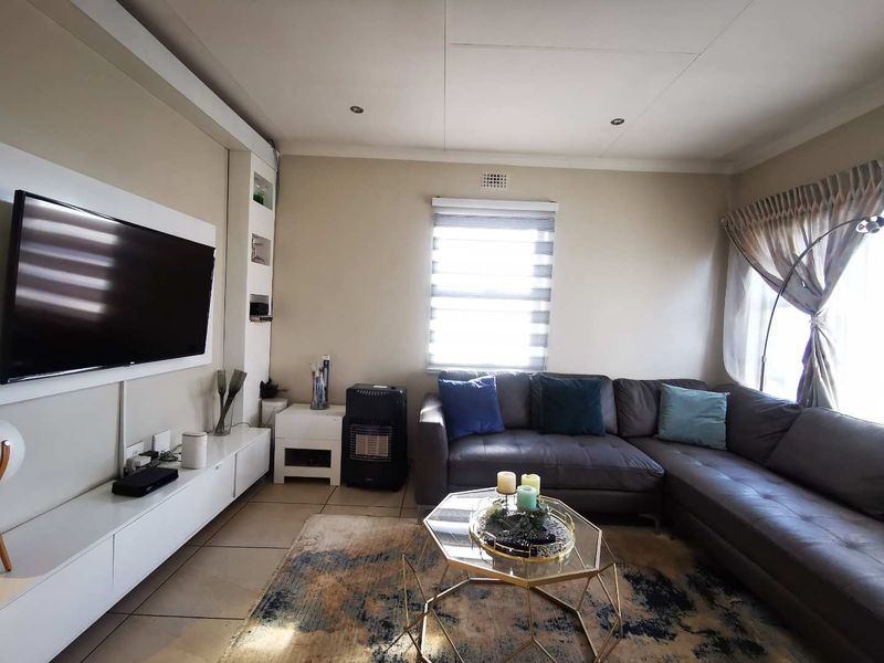 A comfortable living room featuring tiled flooring, recessed downlights, and a built-in media console with integrated shelving.