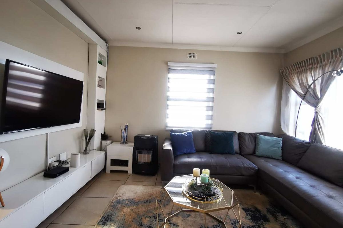 A comfortable living room featuring tiled flooring, recessed downlights, and a built-in media console with integrated shelving.