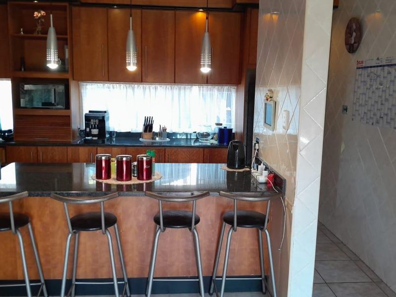 A functional kitchen featuring wooden cabinetry, granite countertops, a breakfast bar, and tiled wall finishes, providing a practical space for cooking and casual dining.