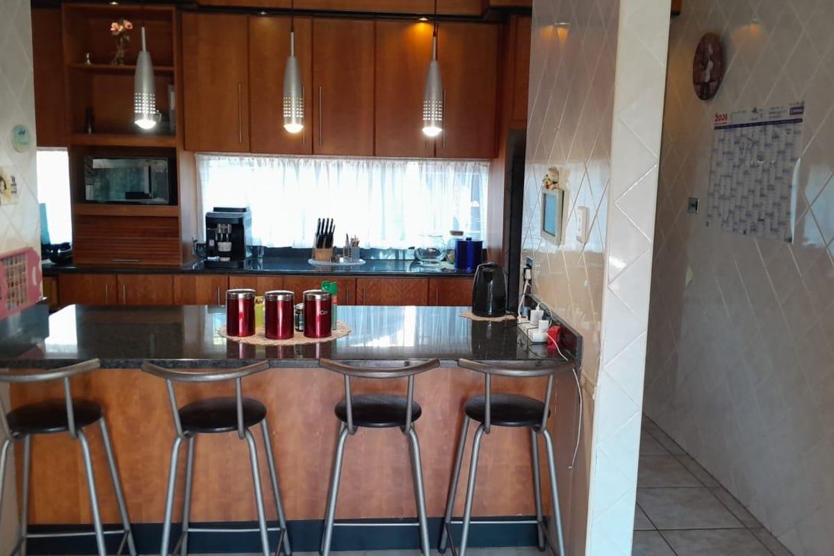 A functional kitchen featuring wooden cabinetry, granite countertops, a breakfast bar, and tiled wall finishes, providing a practical space for cooking and casual dining.