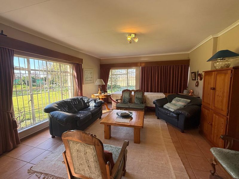 A spacious living room featuring tiled flooring, large windows with security bars, and ample natural light, offering a comfortable and functional living space.