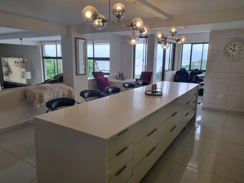 Spacious open-plan living and kitchen area featuring a large central island, sleek cabinetry, tiled floors, and expansive windows with scenic views.