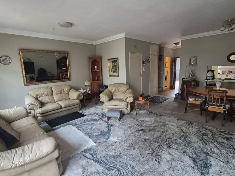 Spacious open-plan living and dining area featuring crown molding, neutral wall tones, and a convenient pass-through window connecting to the kitchen space.