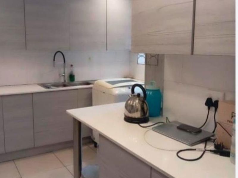 A functional kitchen featuring light wood-grain cabinetry, white countertops, a stainless steel sink, and tiled flooring.