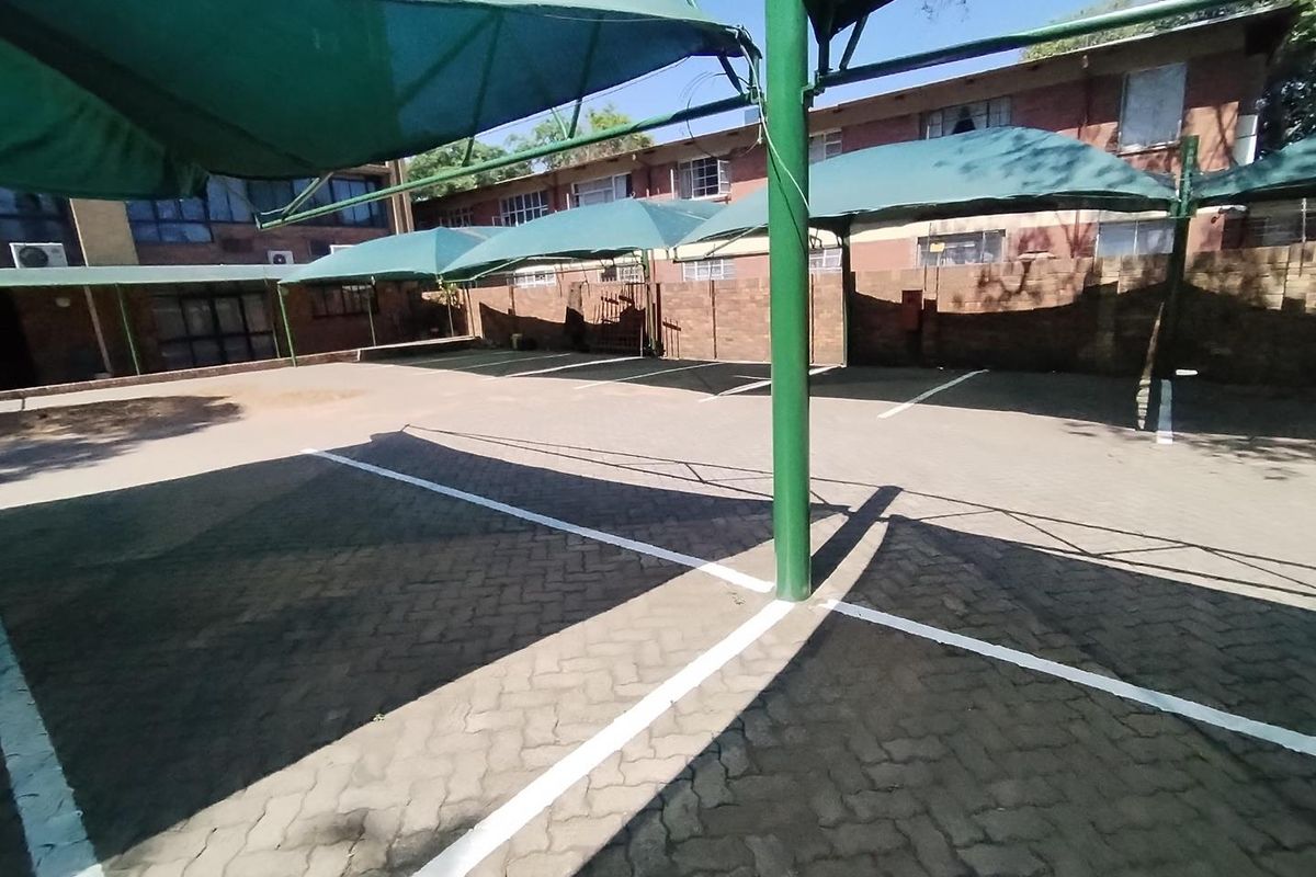 Outdoor parking area featuring paved surfaces and green shade cloth structures for vehicle protection.