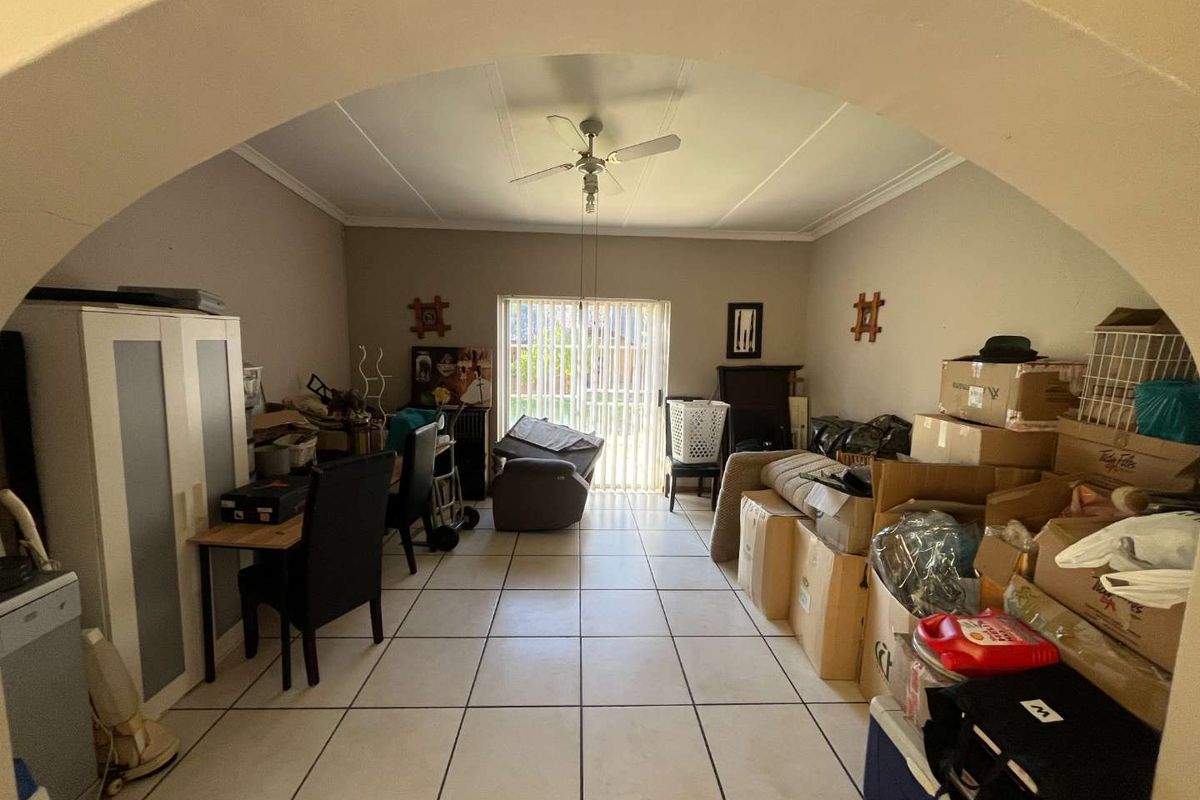 A living area featuring tiled flooring, a ceiling fan, and sliding glass doors leading to the exterior.