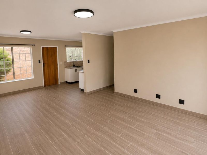 Spacious open-plan living area featuring modern tiled flooring, neutral wall tones, and a functional kitchen nook with built-in cabinetry.