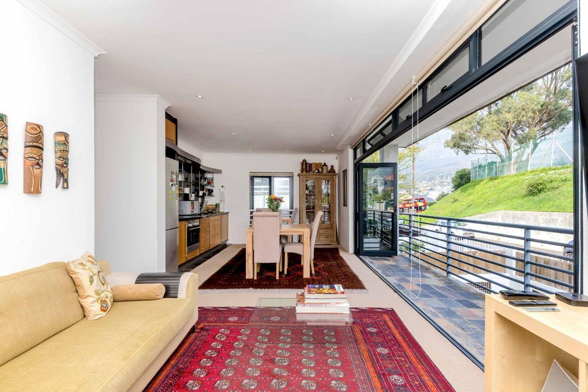 Spacious open-plan living and dining area featuring a modern kitchen and large sliding doors opening onto a balcony with scenic views.