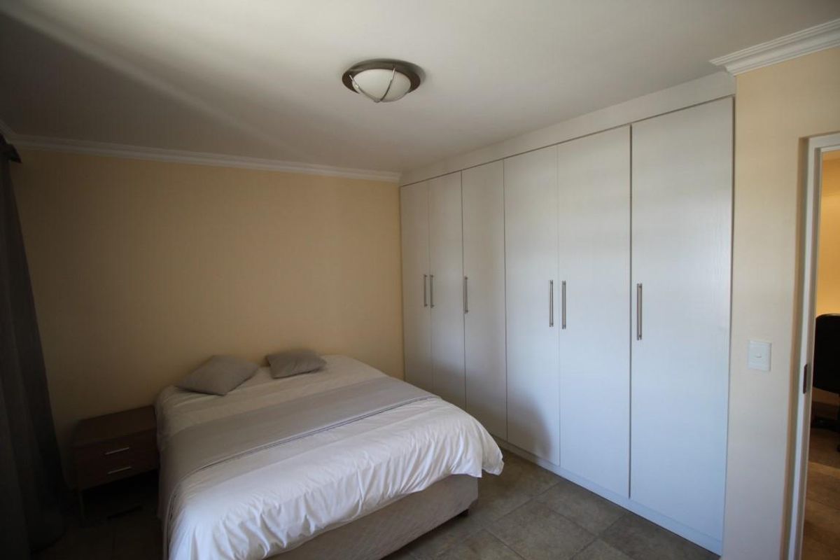 A bedroom featuring built-in floor-to-ceiling wardrobes with modern handles and tiled flooring.