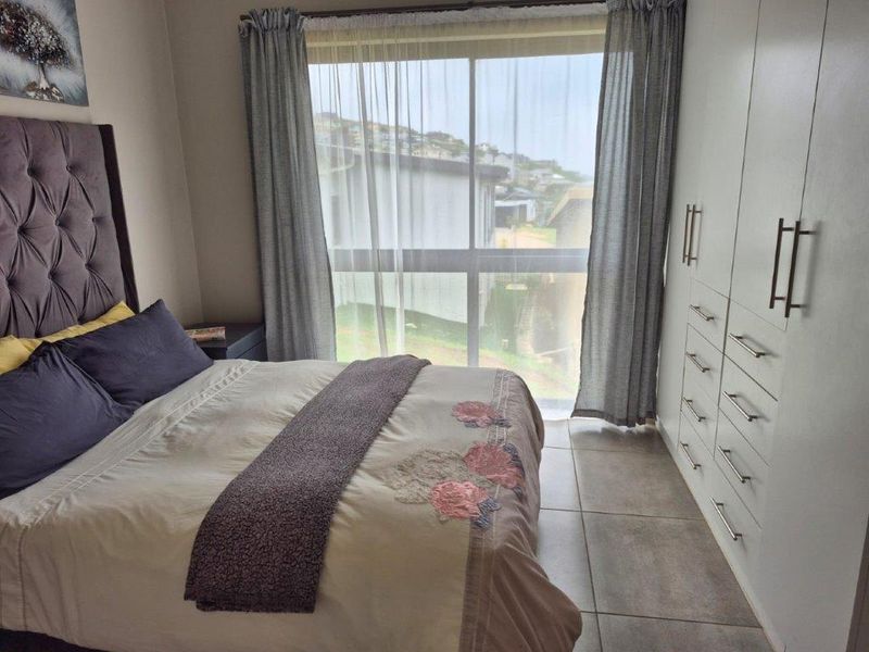 A well-maintained bedroom featuring built-in cupboards, tiled flooring, and a large sliding glass door that provides natural light and exterior views.