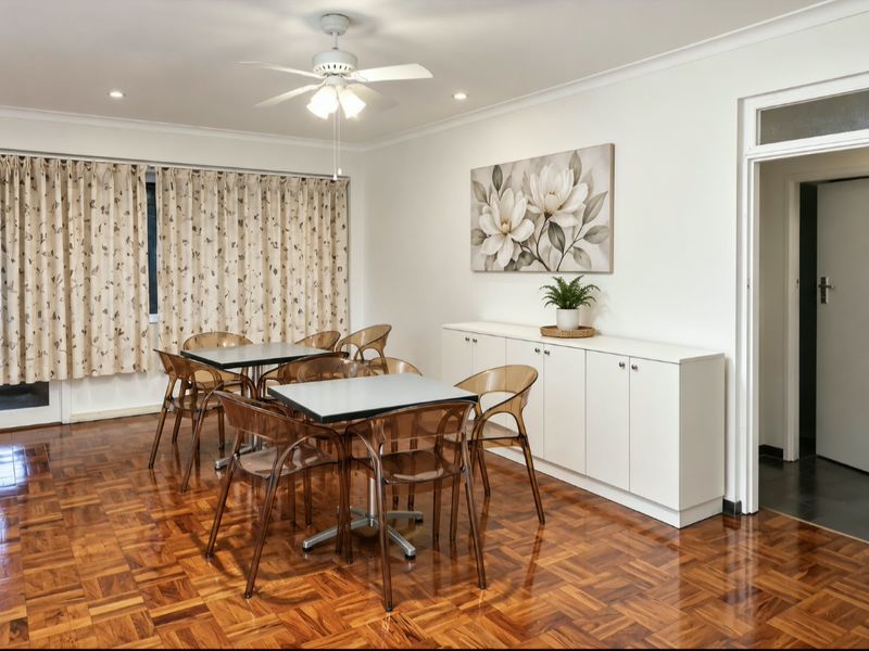 A well-maintained dining area featuring polished parquet flooring, a ceiling fan, and custom built-in cabinetry, offering a clean and functional space.