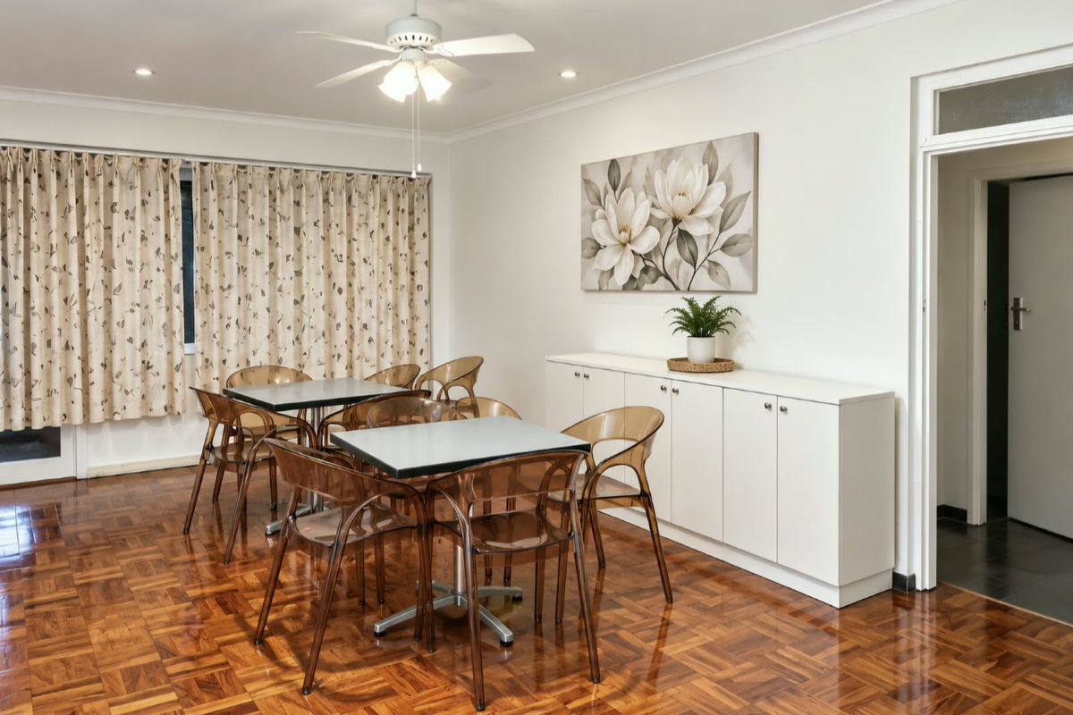 A well-maintained dining area featuring polished parquet flooring, a ceiling fan, and custom built-in cabinetry, offering a clean and functional space.