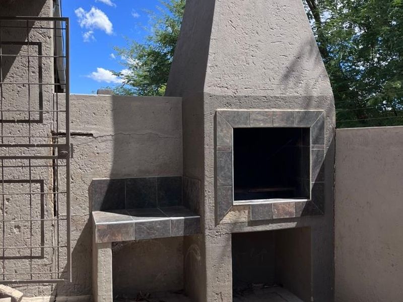 Outdoor patio area featuring a built-in braai with tiled prep counter and paved flooring, ideal for outdoor entertaining.