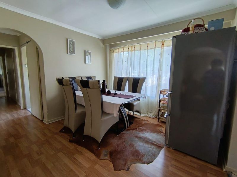 A dining area featuring laminate flooring, an arched entryway, and coved ceilings, providing a functional space for meals.