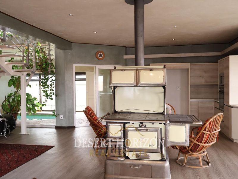 Spacious open-plan living area featuring a unique vintage wood-burning stove, modern laminate flooring, and a striking spiral staircase leading to upper levels.